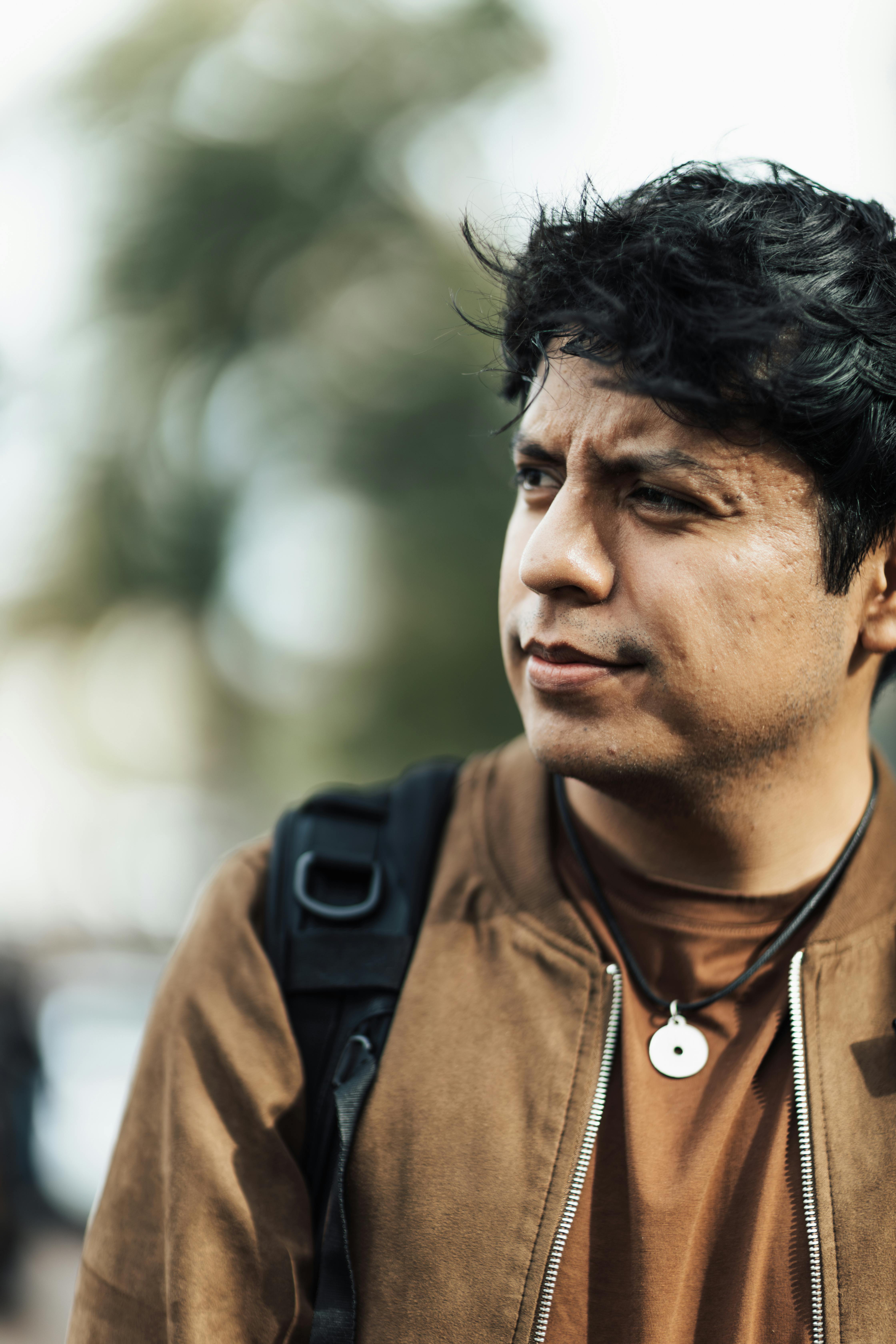 A man with a backpack thoughtfully gazing in an urban setting. Perfect for lifestyle themes.