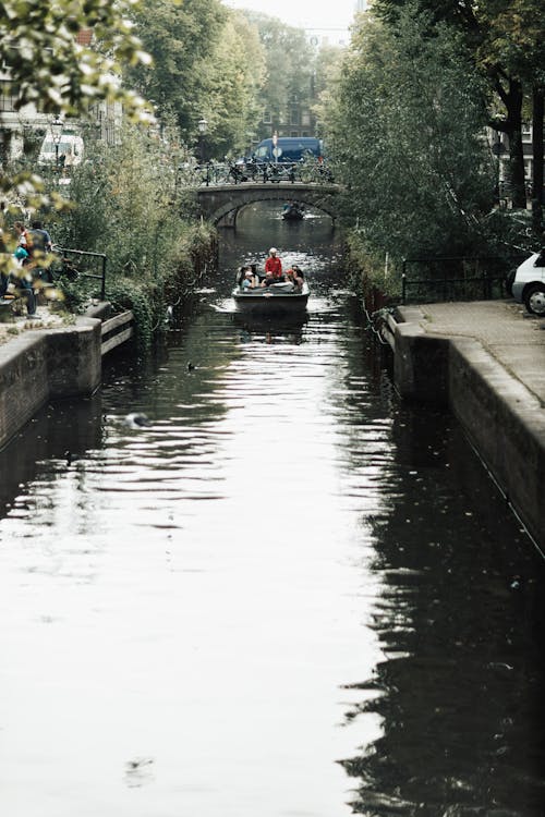 People on Motorboat on Canal in Town