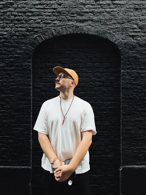 Man in a Cap Standing by a Black Brick Wall