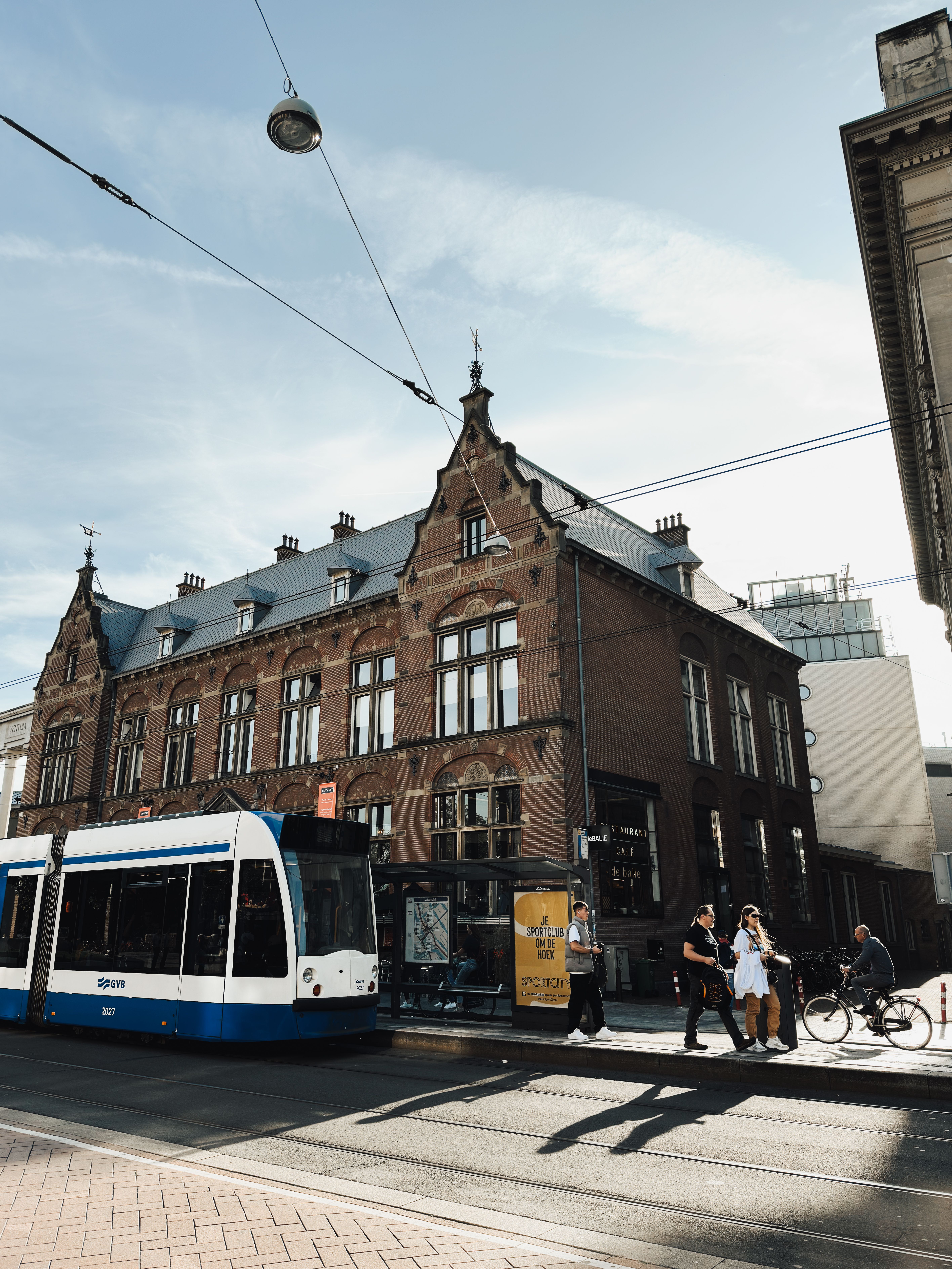 Charming Amsterdam street scene with a classic tram passing historic Dutch architecture.