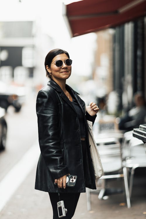 Smiling Woman in a Leather Coat and Sunglasses