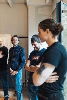 A group of men casually interacting in a modern office environment with natural lighting.