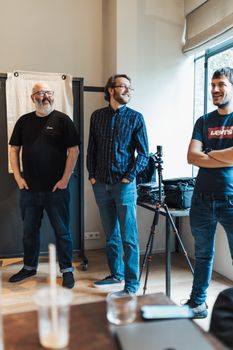 Three men standing in a casual office environment, sharing a light moment.