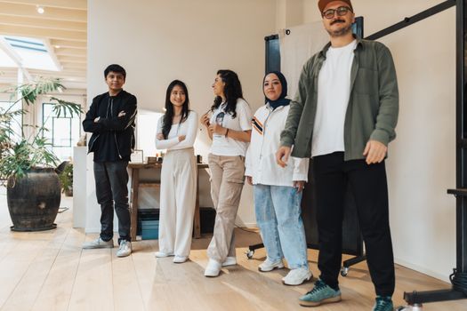 Diverse group of young professionals smiling in a modern office environment, highlighting teamwork and inclusivity.