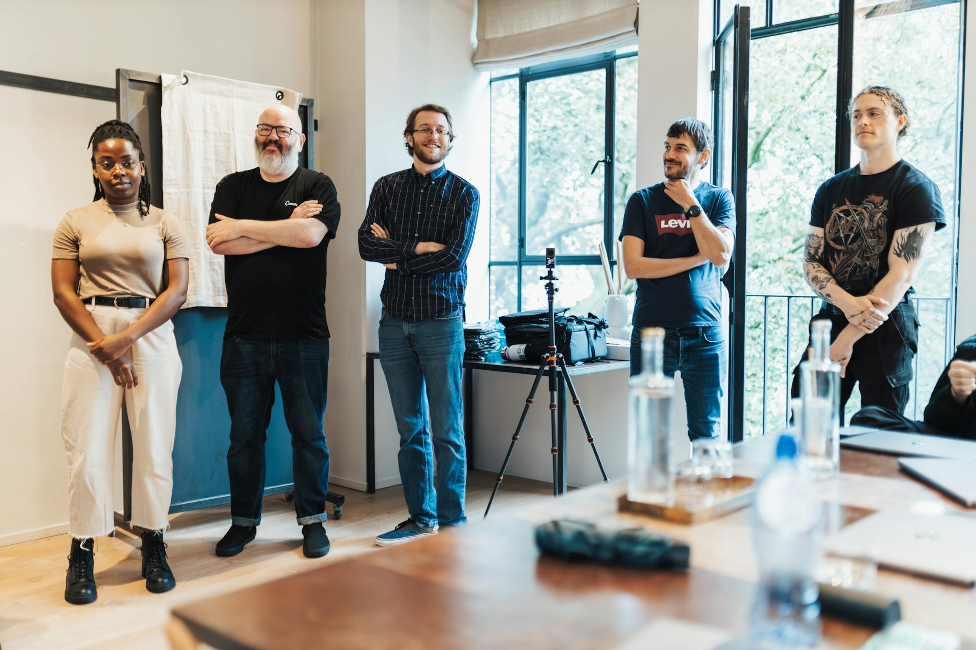 A group of five diverse adults engaging in a casual meeting in a contemporary office setting.