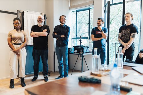 Free A group of five diverse adults engaging in a casual meeting in a contemporary office setting. Stock Photo