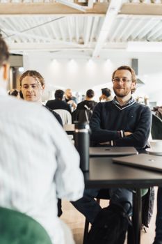 Group of adults in a meeting at a modern office setting, engaged in discussion.