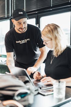 Two colleagues collaborating with laptops in a bright, modern office.