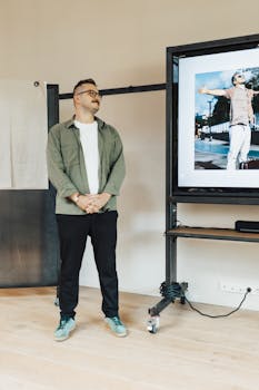 A man delivers a presentation in a modern office with a large screen display.