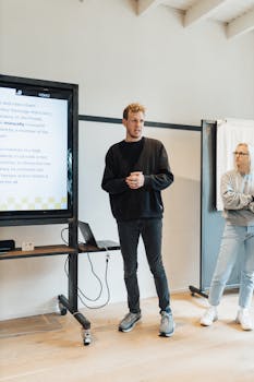 Business professionals conducting a presentation for team collaboration, featuring digital screen and open discussion.