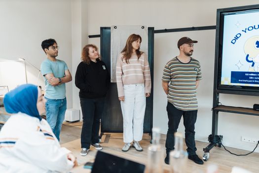 Diverse group of adults attentively watching a presentation in a bright modern office setting.