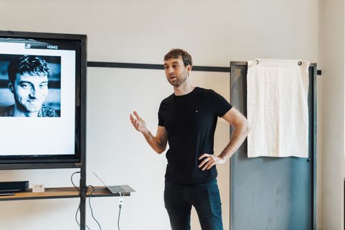Free Young man giving a presentation using a projector in a contemporary office setting. Stock Photo