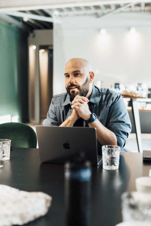 Free Professional businessman discussing at a café, using a laptop, conveying a relaxed and modern work atmosphere. Stock Photo