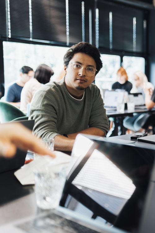 Free A man focused on work in a modern coworking space with colleagues in the background. Stock Photo