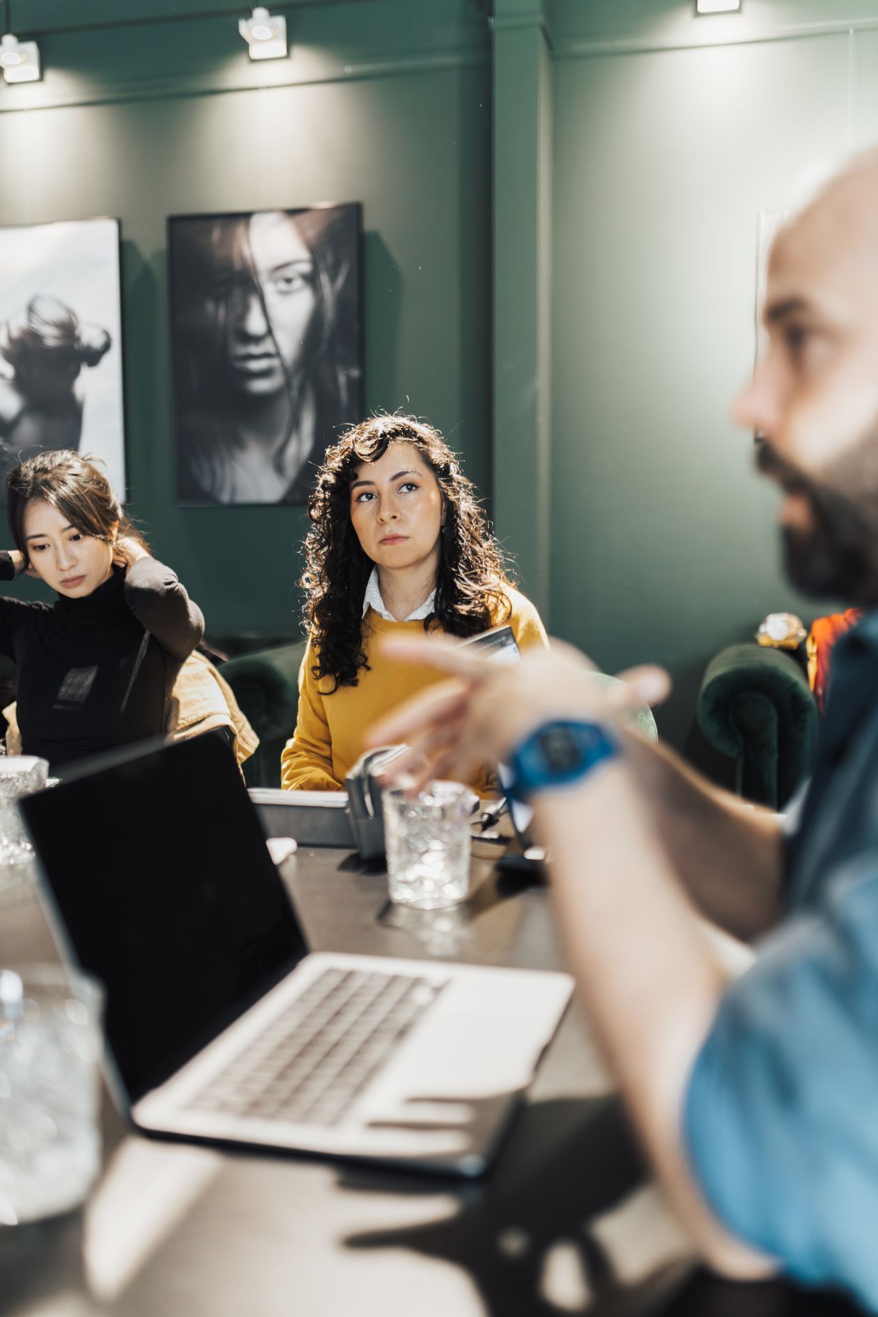 Professionals discussing projects around a conference table with laptops and notepads