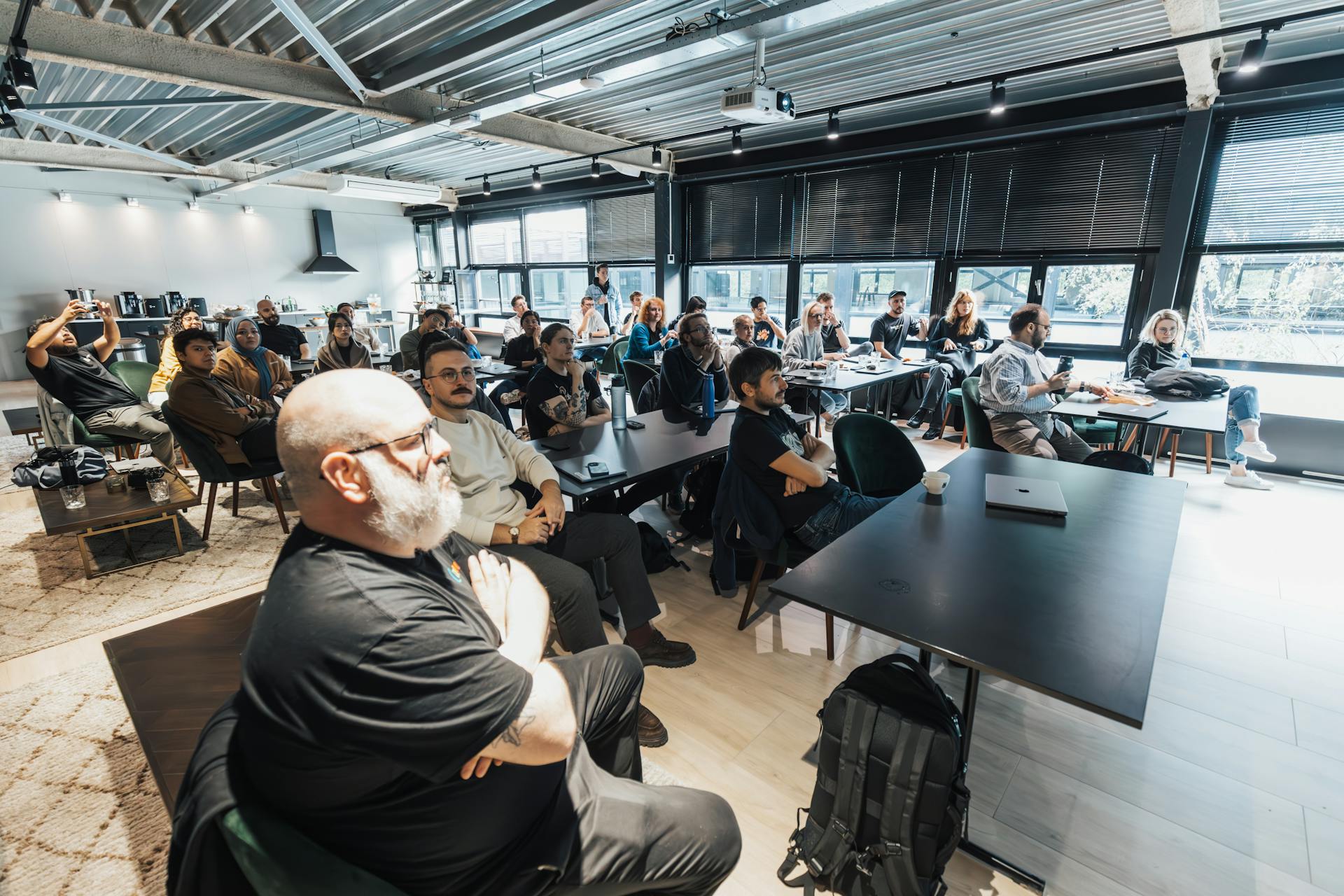 A diverse group of professionals attentively listening during an indoor business meeting in a modern conference room.