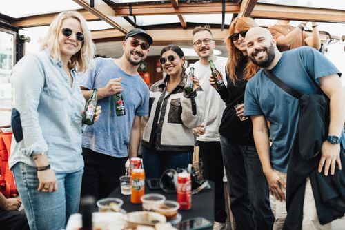 Free Six friends smiling and holding drinks on a sunny boat party outing. Stock Photo
