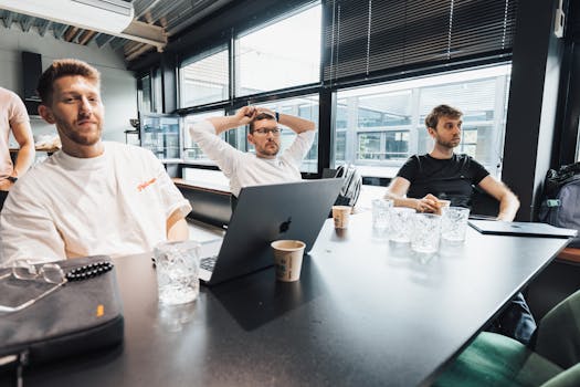 Three men casually working together in a bright modern office space.