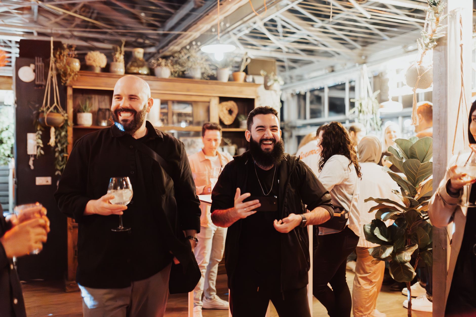 A lively indoor gathering with people enjoying drinks, laughter, and social interactions.