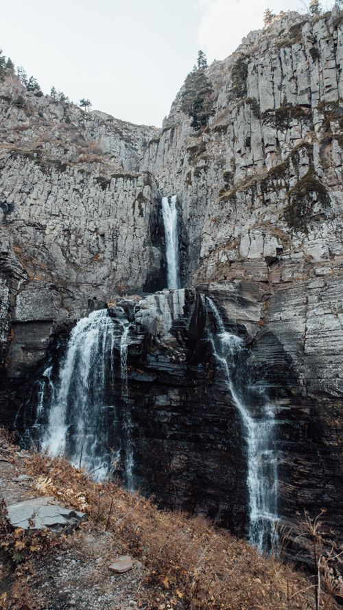 Free Captivating waterfall cascading down rugged cliffs surrounded by autumn foliage. Stock Photo