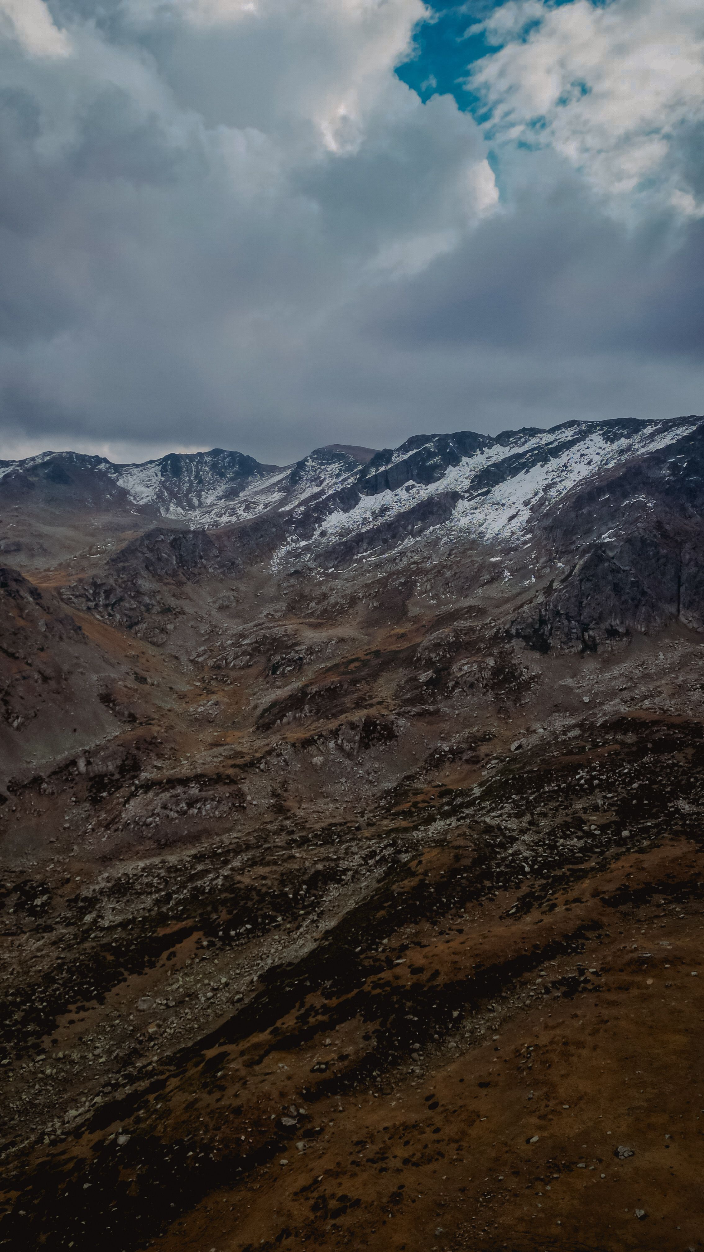 Majestic snow-covered mountains under a dramatic cloudy sky, epitomizing serene wilderness.
