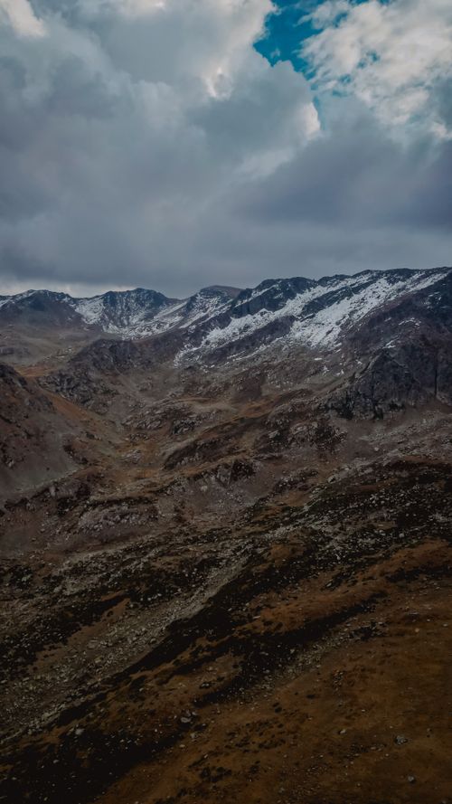 Free Majestic snow-covered mountains under a dramatic cloudy sky, epitomizing serene wilderness. Stock Photo