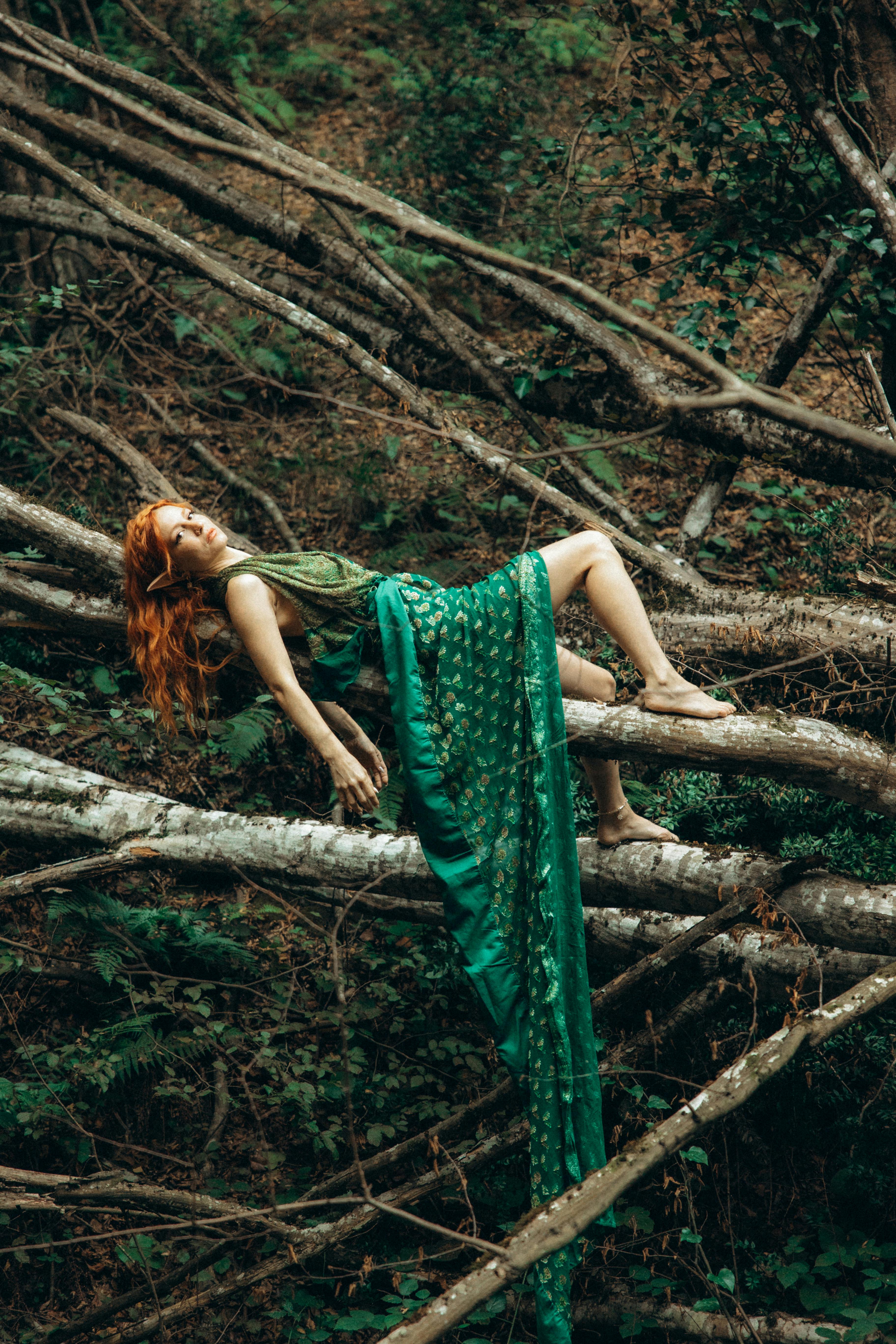 a woman laying on a tree branch in green dress