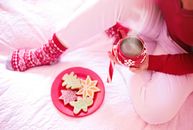 A woman relaxing with a hot chocolate and Christmas cookies in a cozy winter setting.