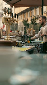Bustling outdoor bar with a bartender preparing drinks in a city setting.