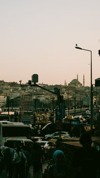 Traffic and city life in Istanbul with a mosque silhouette at dusk.