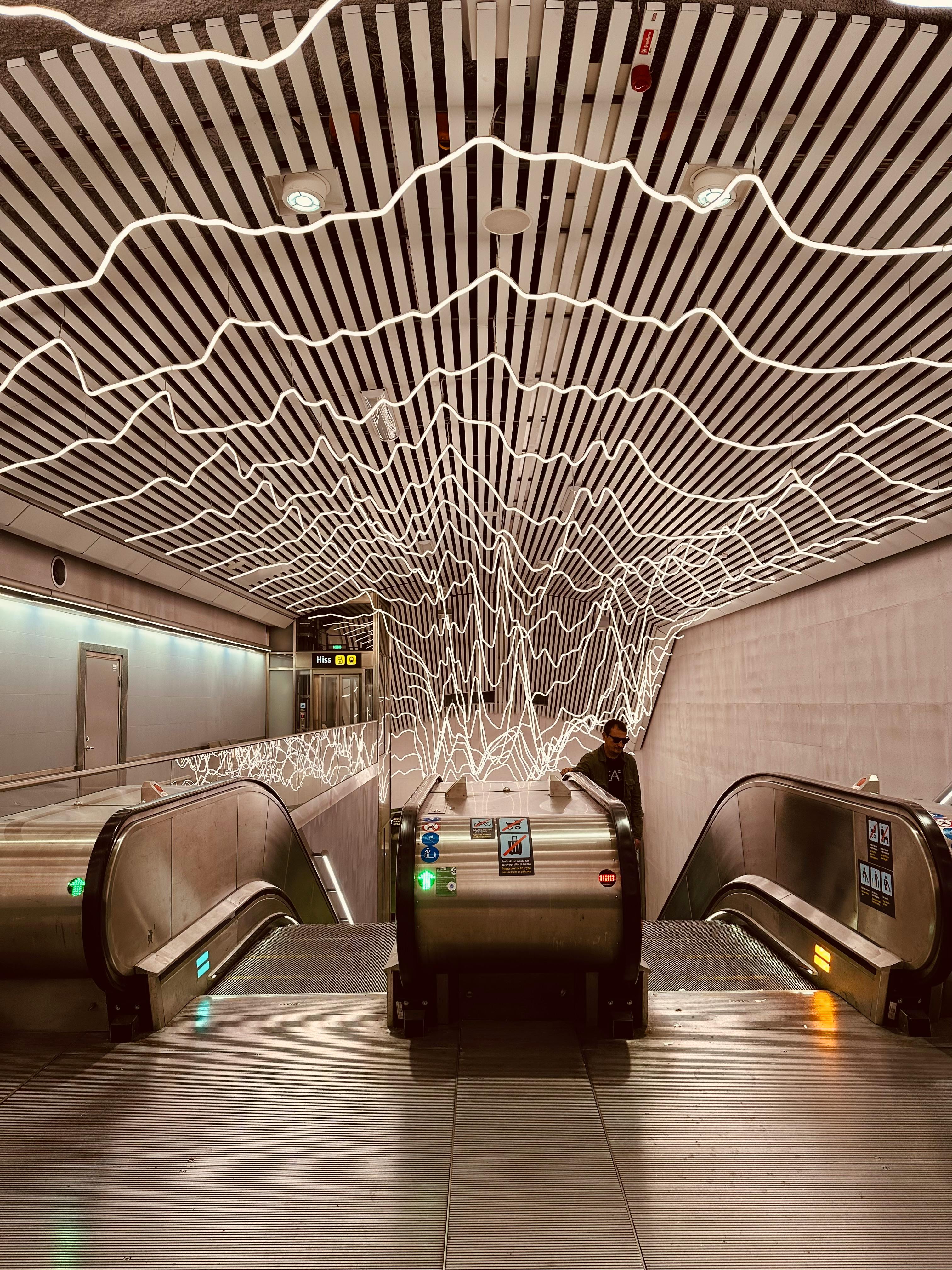 Illuminated artistic ceiling in a Stockholm metro station with escalators.