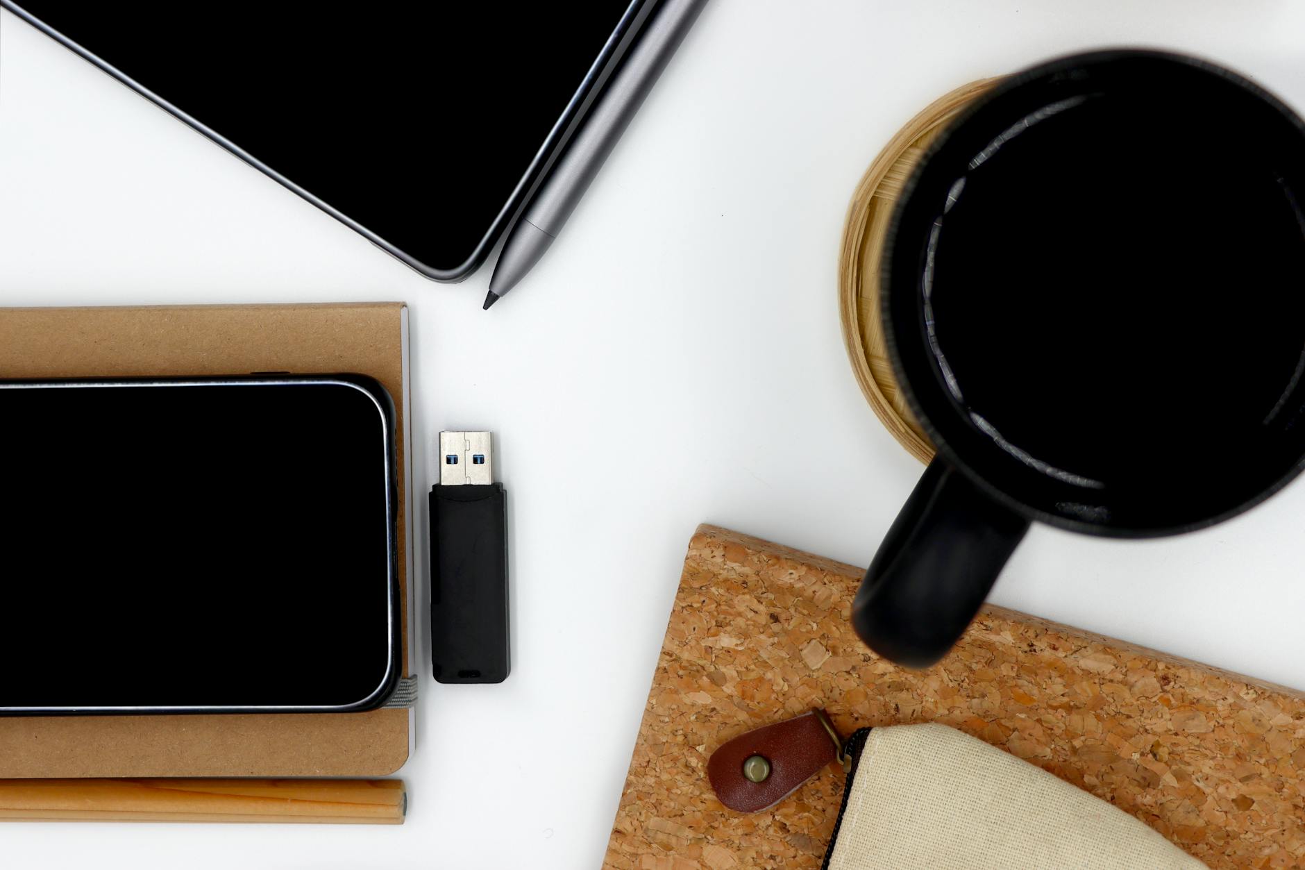 Top view of a modern work desk with coffee, gadgets, and stationery.