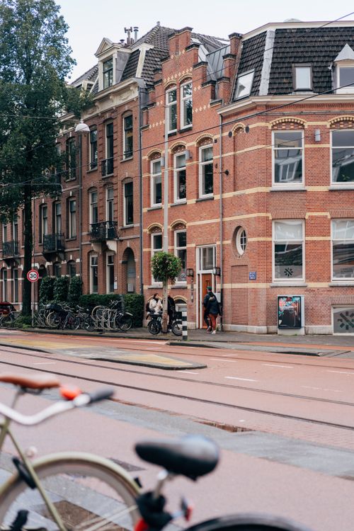 Free Beautiful Amsterdam townhouses with bicycles parked, capturing urban life on a quiet city street. Stock Photo