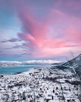 粉红色的天空下，白雪皑皑的斯堪的纳维亚小镇在日落时分被捕捉，构成了一幅令人惊叹的冬日景象
