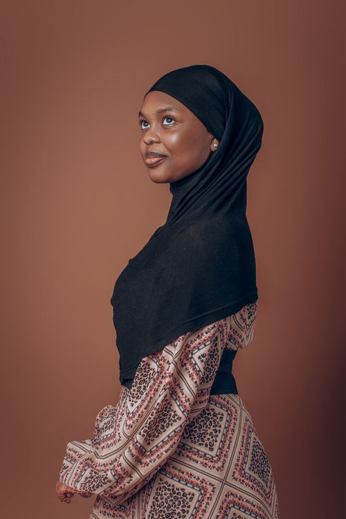 Free Side profile portrait of an African woman wearing a black headscarf, in a studio setting. Stock Photo