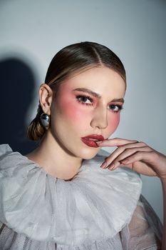 Close-up portrait of a woman in stylish fashion with dramatic makeup and elegant attire.