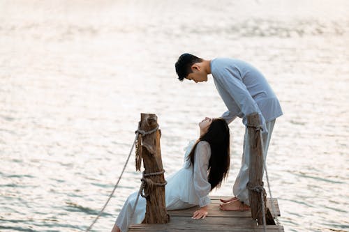 Couple on Wooden Pier Looking at Each Other Eyes