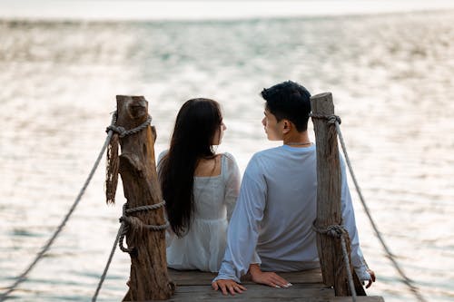 Couple Sitting Together on Wooden Pier on Seashore