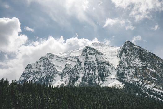 Breathtaking view of snow-capped Rocky Mountains in Banff, Alberta, under a cloudy sky.