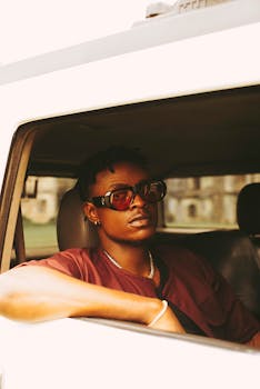 Cool and confident young man in sunglasses sitting in a vehicle window.