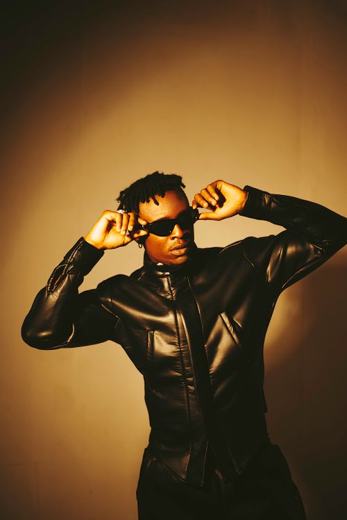 Free Confident man in a leather jacket and sunglasses posing in a modern fashion shoot. Stock Photo