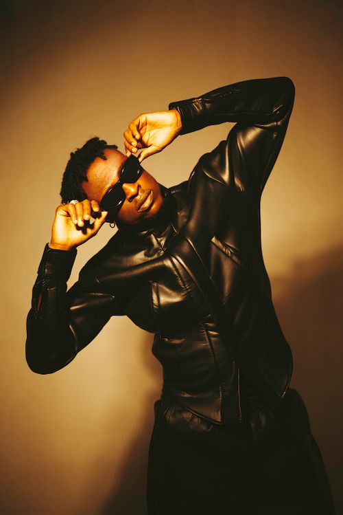 Free Fashionable black man in a black leather jacket and sunglasses striking a pose indoors. Stock Photo