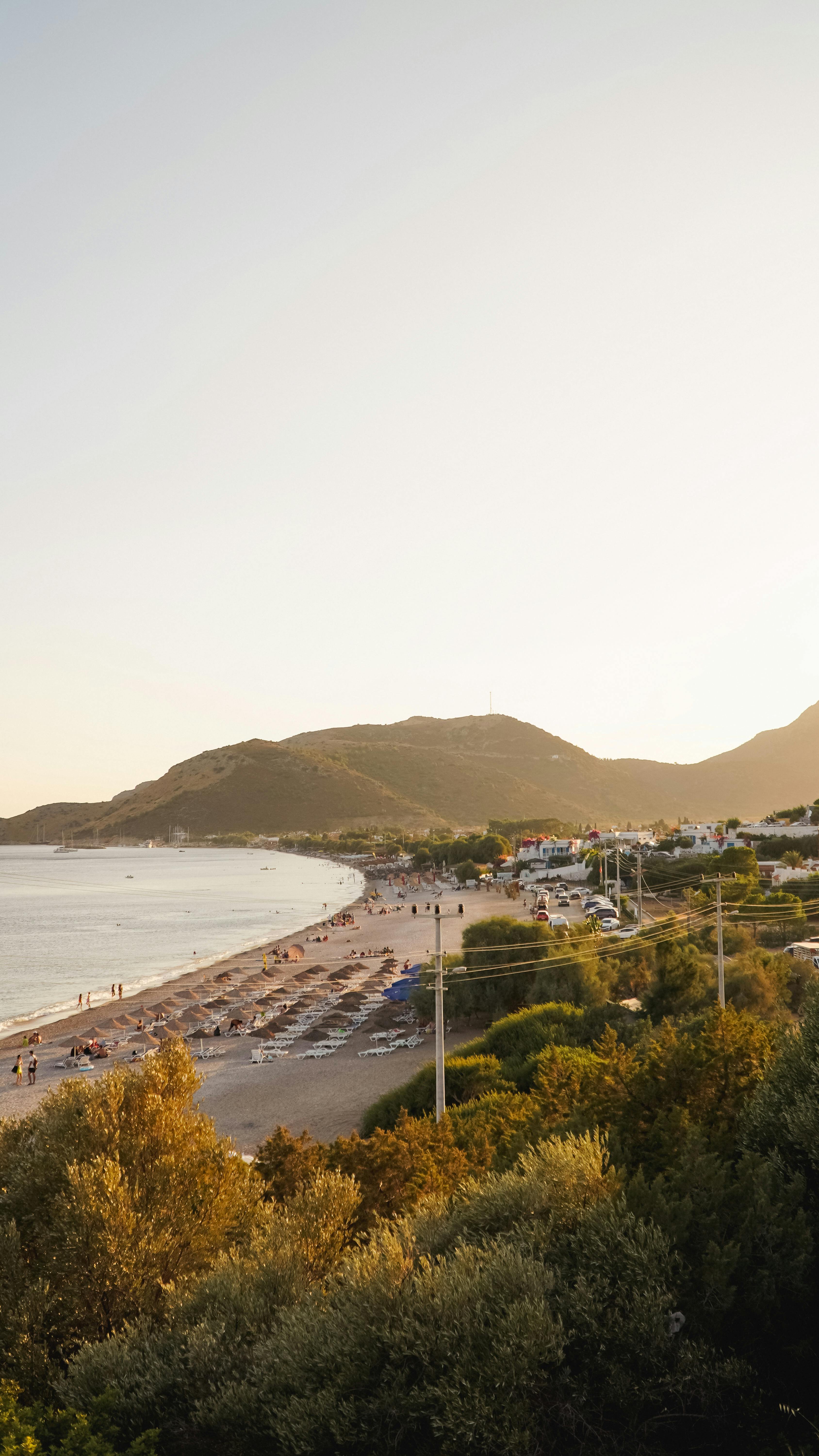 A serene coastal view of Muğla, Türkiye, captured at sunset with mountains and sea.