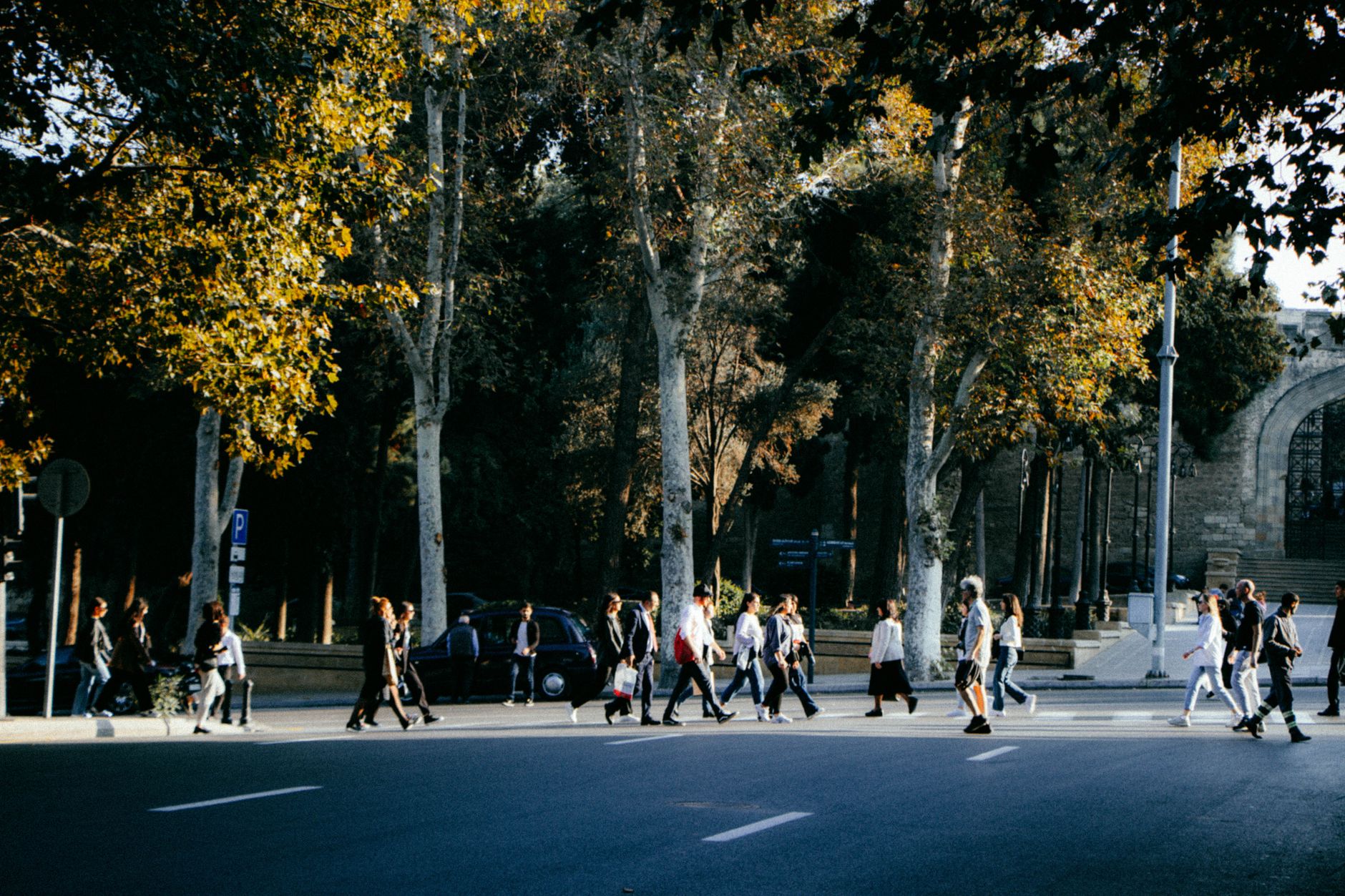 Pedestrians on a tree-lined Nairobi pavement in afternoon light