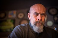 一位留着胡须的秃头男子在艺术室内环境中的特写肖像，展现出深思熟虑的表情