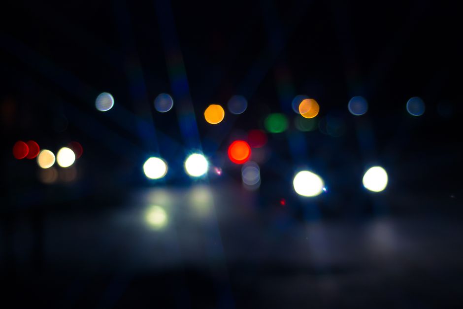 Oncoming headlights blurring into starbursts and halos as seen through a car windshield at night