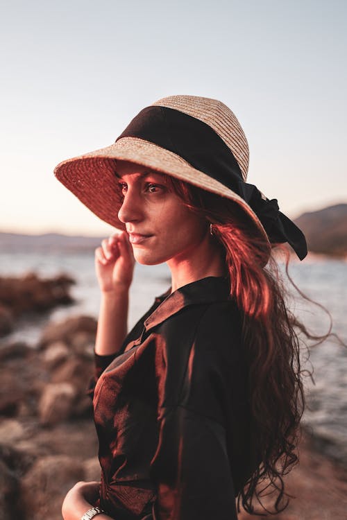 Woman in Hat and Black Shirt on Sea Shore