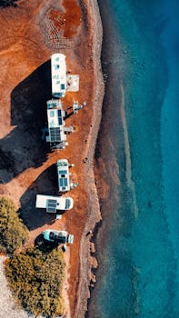 Overhead view of parked campers lined on the Marmaris shore, overlooking the clear turquoise sea.