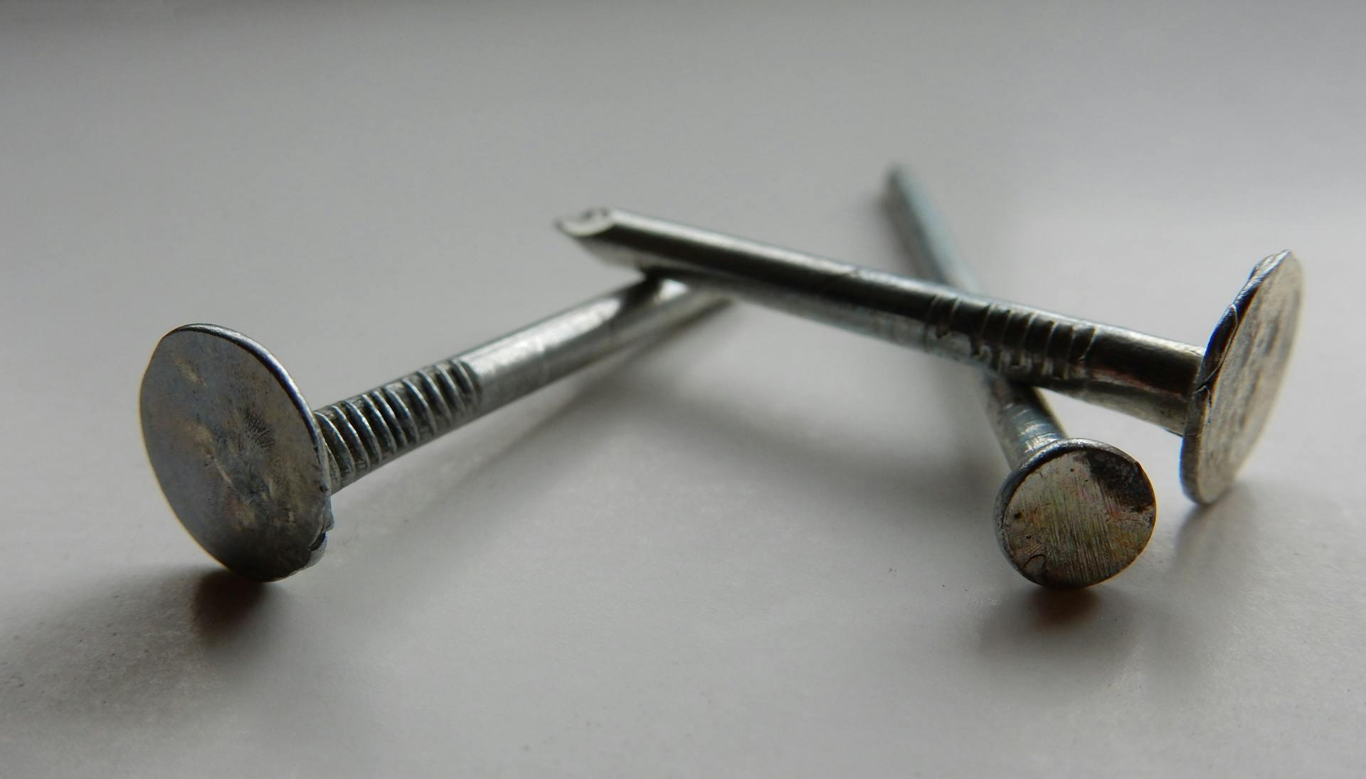 Detailed image of three metallic nails on a white background, highlighting texture and shape.