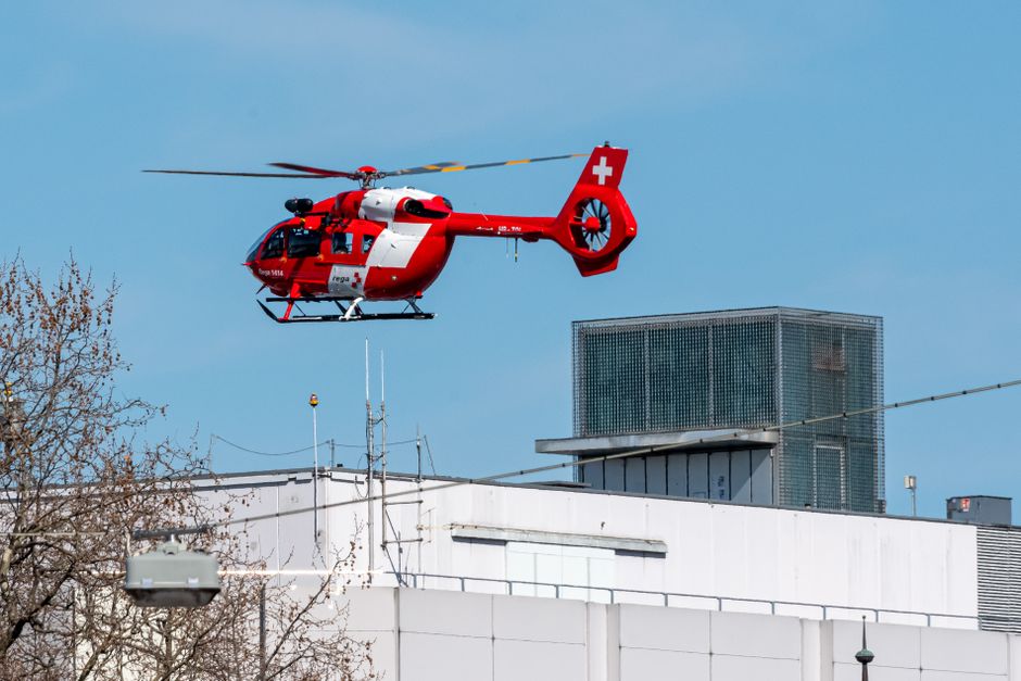 A red rescue helicopter in flight over an urban rooftop, symbolizing fast emergency response.